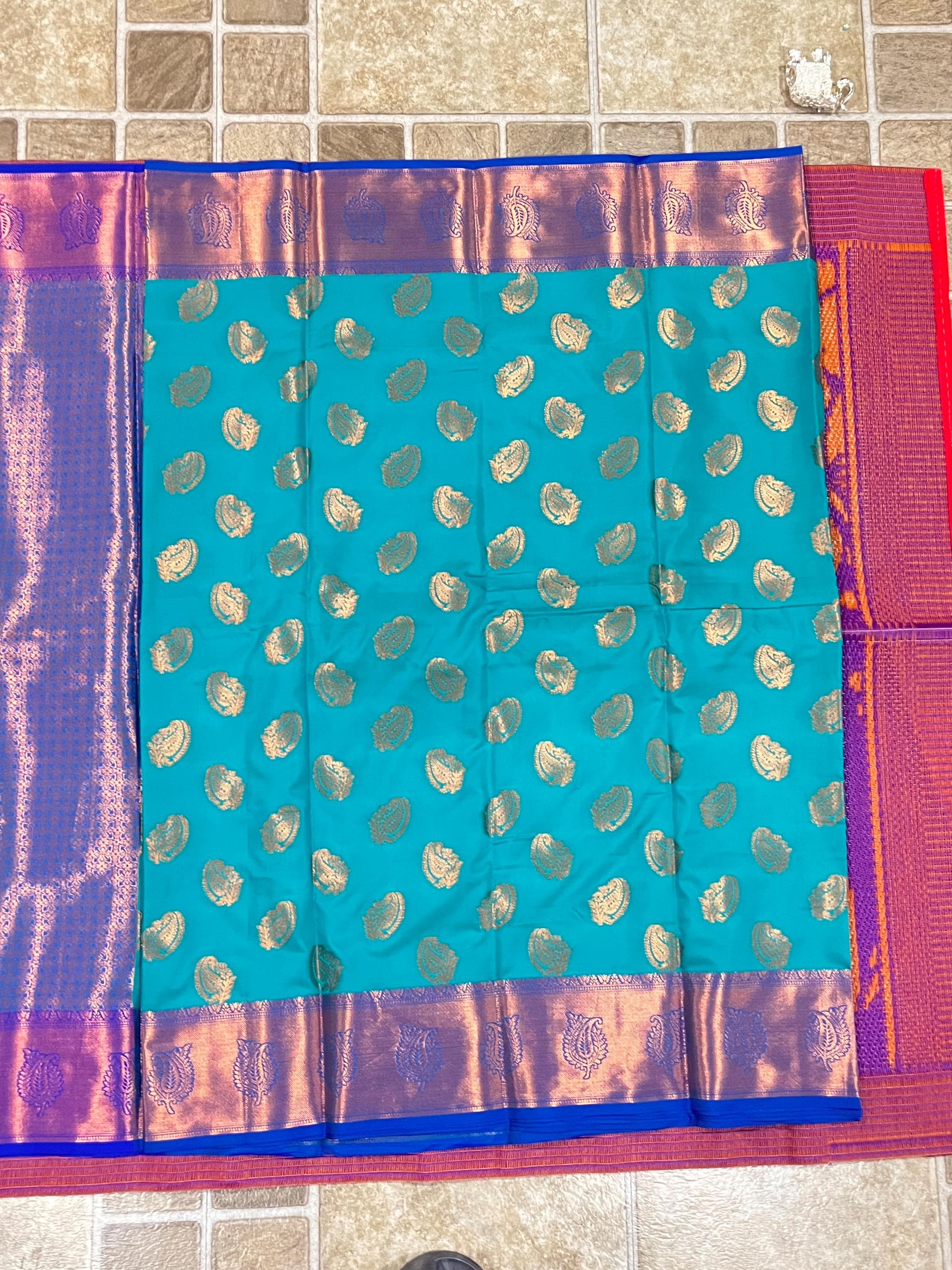Turquoise handwoven Kanchi silk saree with gold zari paisley motifs and purple borders.