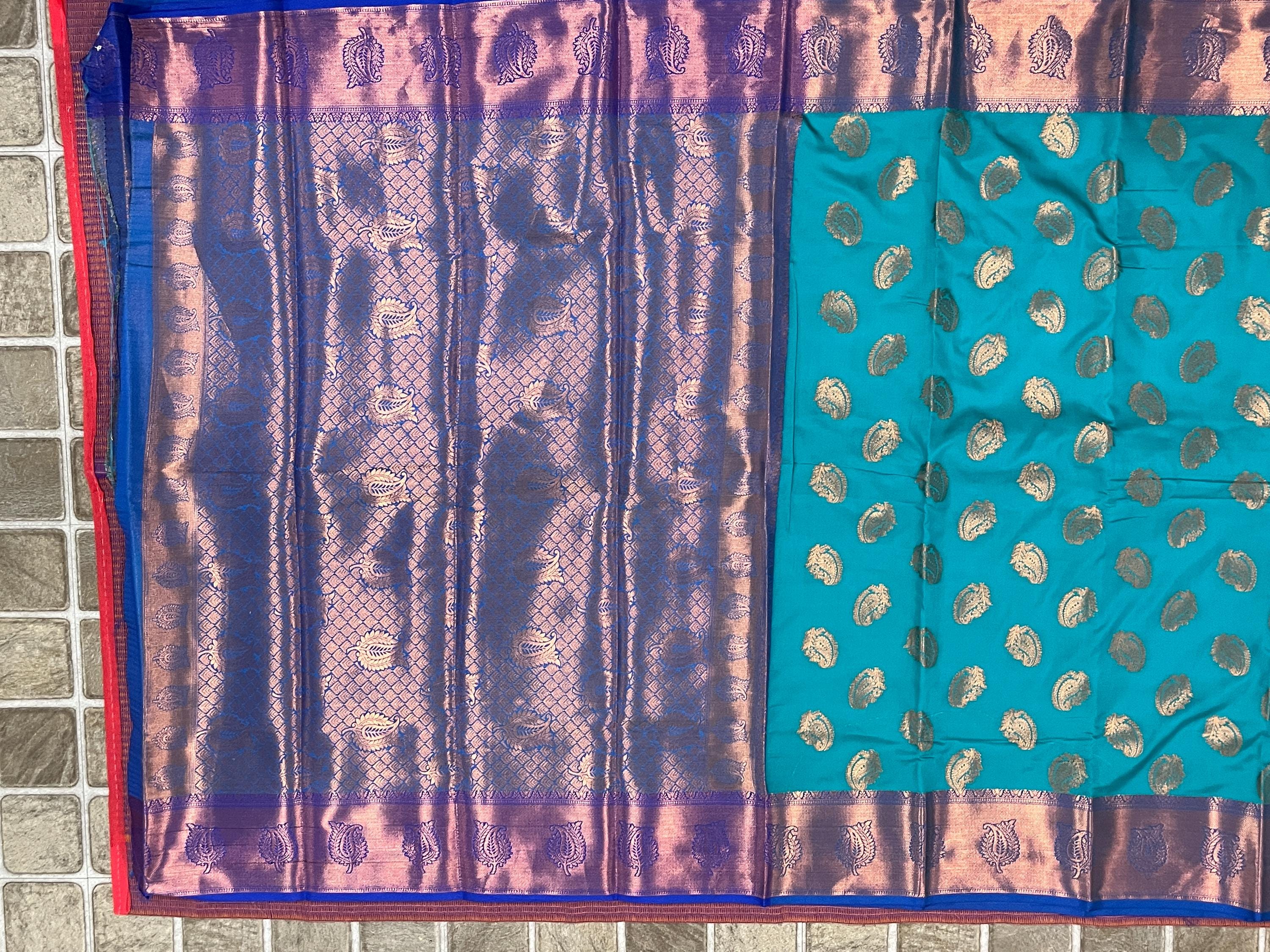 Handwoven Kanchi silk saree in teal with gold zari motifs and purple brocade border.