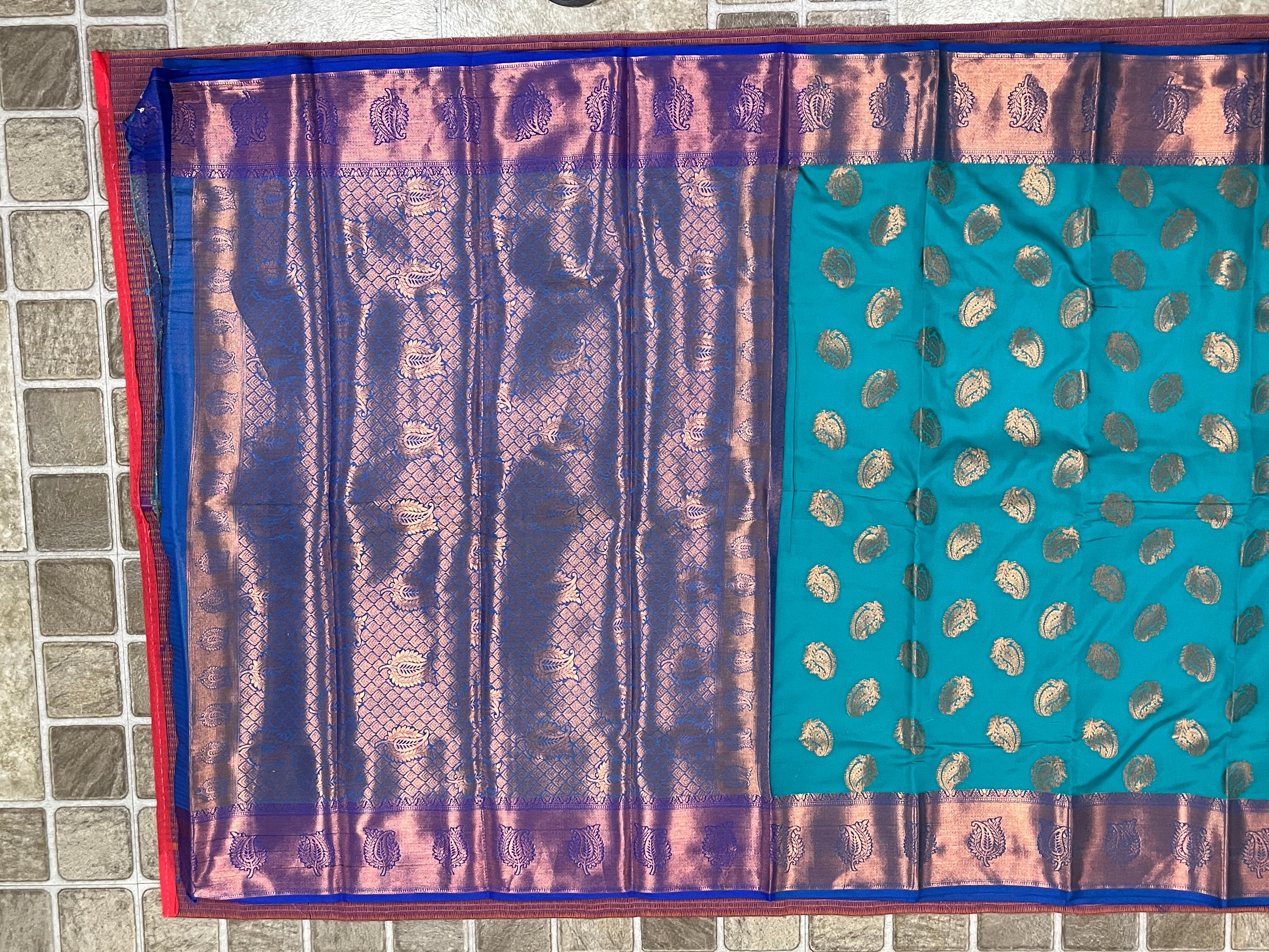 Handwoven Kanchi silk saree with zari border; turquoise body adorned with gold paisley motifs.