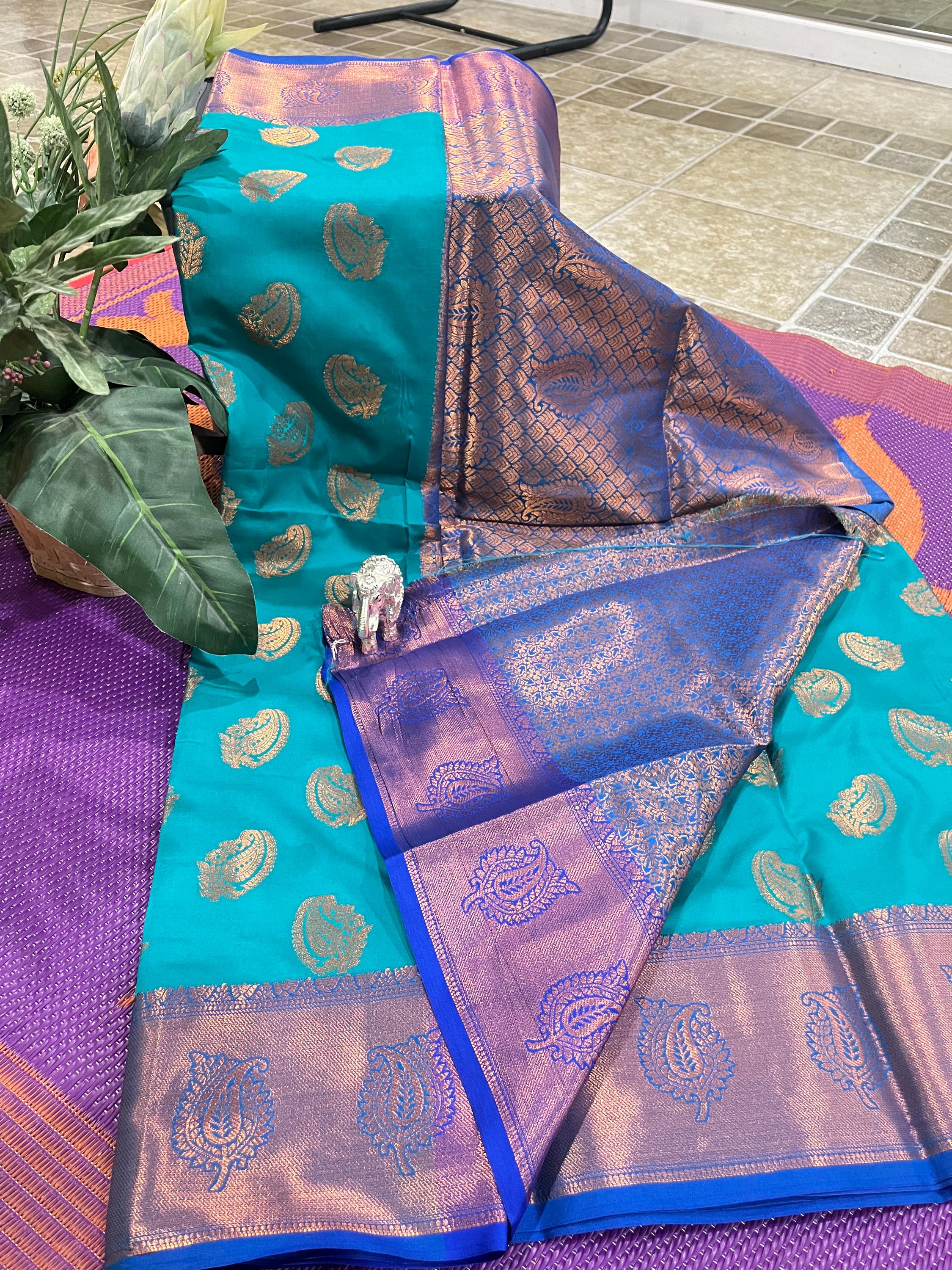 Handwoven Kanchi silk saree in teal and purple with gold zari work and wedding-ready paisley motifs.
