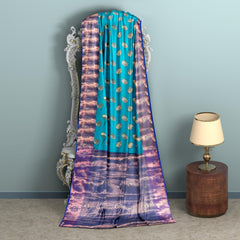 Handwoven Kanchi silk saree with zari work for weddings, turquoise with purple border, draped over an ornate mirror.